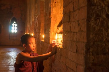 Eski tapınağın içinde mum yanan küçük keşiş. Bagan. Myanmar.