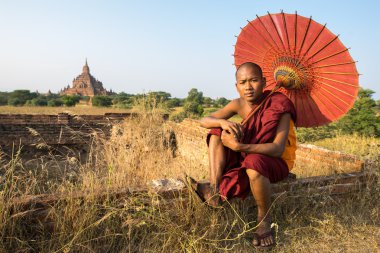 Acemi monk kırmızı şemsiye ile Sulamani pagodadan önünde duruyor. Baga