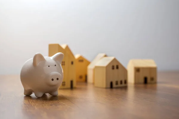 Piggy bank and wooden house on wooden desk,  Save money and buy house concept.