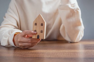 Ahşap masada ahşap evi tutan kadın, para biriktir ve ev konsepti al..