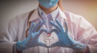 Doktor ya da bilim adamı ellerinde sıvı aşılar ve kalp şeklinde jestler tutan koruyucu eldivenler tutuyor. Aşı ve bağışıklık. hastalıklar, tıbbi bakım, bilim, aşı destekleyici kavram.