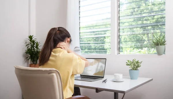 Office syndrome concept. Woman using hand to massage her neck feeling pain in neck after working on computer laptop for long time, neck fatigue, muscle pain or incorrect posture when using laptop.