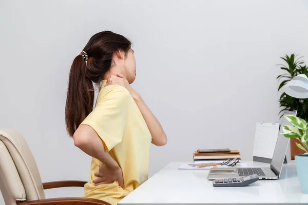 Office syndrome concept. Woman using hand to massage her neck and  pain in back feeling pain in neck after working on computer laptop for long time, neck fatigue, muscle pain.