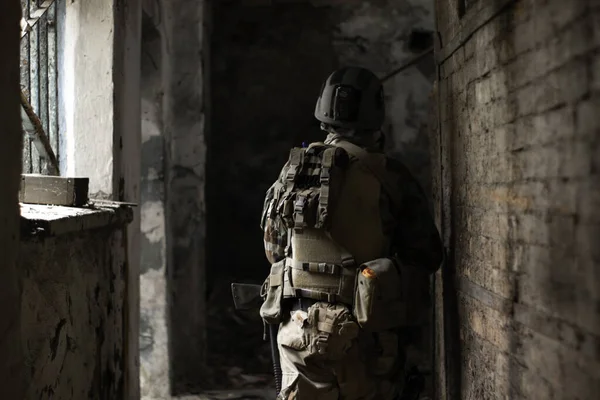 古い放棄された通路で米軍の制服を着た男が銃とエアソフトスポーツゲームで動きます — ストック写真