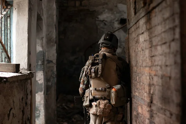 古い放棄された通路で米軍の制服を着た男が銃とエアソフトスポーツゲームで動きます — ストック写真