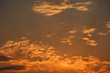 Karanlık dağ siluetlerinin üzerinde turuncu ve kırmızı tonlarda parlayan katmanlı bulutlarla dramatik, ateşli günbatımı, Ağustos 2025 'te yakalandı.
