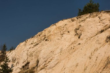 Engebeli bir dağ silsilesi dramatik katmanlı bulutların altında yükselir, karamsar ve atmosferik doğal bir manzara yaratır..