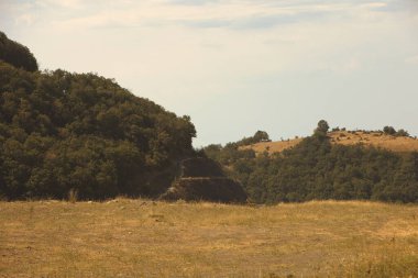 Engebeli yamaçları olan manzaralı bir dağ manzarası, dağınık bitki örtüsü Ağustos 2025