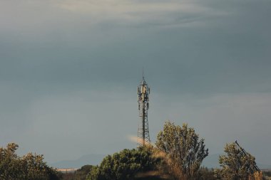 Yüksek voltajlı bir güç iletim kulesi dramatik, fırtınalı bir gökyüzüne karşı duruyor..
