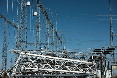 Yüksek voltajlı bir elektrik iletim kulesinin, açık mavi gökyüzüne karşı birden fazla elektrik hattı olan yakın görüntüsü, Ağustos 2025 'te bir yol gezisi sırasında çekildi.