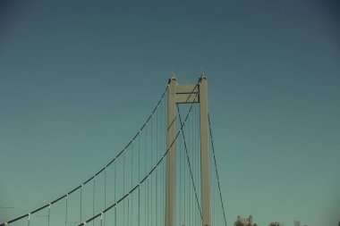 Açık mavi gökyüzünün altında düz bir kırsal alana yayılan büyük modern asma köprü, 2025 Ağustos 'unda yol kenarından çekilmiş..