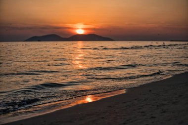 Vlora, Arnavutluk 21 Ağustos 2025. Adriyatik Denizi 'nin üzerinde sakin bir günbatımı. Sıcak altın ışık, yumuşak dalgalar ve uzak dağ siluetleri arasında yansıyor..