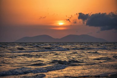 Vlora, Arnavutluk 21 Ağustos 2025. Adriyatik Denizi 'nin üzerinde sakin bir günbatımı. Sıcak altın ışık, yumuşak dalgalar ve uzak dağ siluetleri arasında yansıyor..