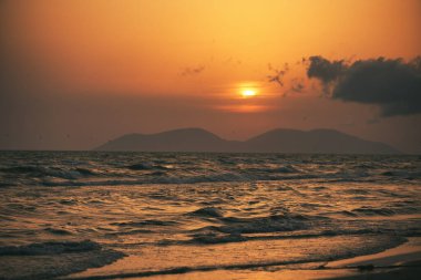 Vlora, Arnavutluk 21 Ağustos 2025. Adriyatik Denizi 'nin üzerinde sakin bir günbatımı. Sıcak altın ışık, yumuşak dalgalar ve uzak dağ siluetleri arasında yansıyor..