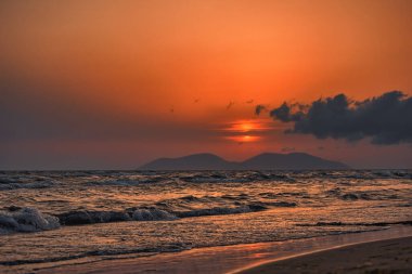 Vlora, Arnavutluk 21 Ağustos 2025. Adriyatik Denizi 'nin üzerinde sakin bir günbatımı. Sıcak altın ışık, yumuşak dalgalar ve uzak dağ siluetleri arasında yansıyor..