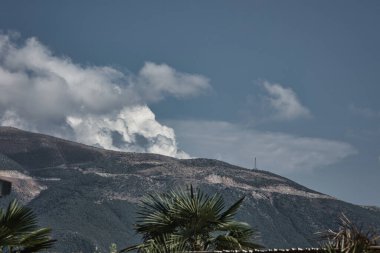 Vlora, Albania  August  2025, A calm mountain landscape overlooking scattered hillside homes under a clear blue sky, with birds gliding gracefully above the rugged terrain. The warm afternoon light highlights the textures of the slopes .