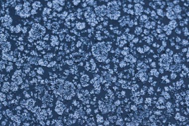 Donmuş bir yüzeyde buz kristali desenleri olan soyut kış soğuğu dokusu. Kar tanesi gibi detaylara sahip doğal buzlu arka plan mevsimlik tasarımlar, soğuk hava konseptleri ve kış tatili temaları için mükemmel..