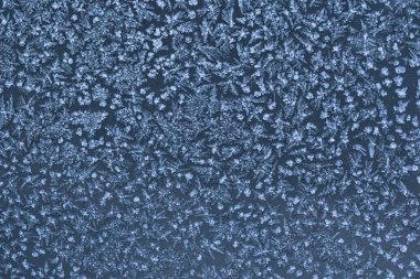 Donmuş bir yüzeyde buz kristali desenleri olan soyut kış soğuğu dokusu. Kar tanesi gibi detaylara sahip doğal buzlu arka plan mevsimlik tasarımlar, soğuk hava konseptleri ve kış tatili temaları için mükemmel..