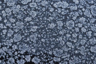 Donmuş bir yüzeyde buz kristali desenleri olan soyut kış soğuğu dokusu. Kar tanesi gibi detaylara sahip doğal buzlu arka plan mevsimlik tasarımlar, soğuk hava konseptleri ve kış tatili temaları için mükemmel..