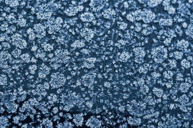 Donmuş bir yüzeyde buz kristali desenleri olan soyut kış soğuğu dokusu. Kar tanesi gibi detaylara sahip doğal buzlu arka plan mevsimlik tasarımlar, soğuk hava konseptleri ve kış tatili temaları için mükemmel..