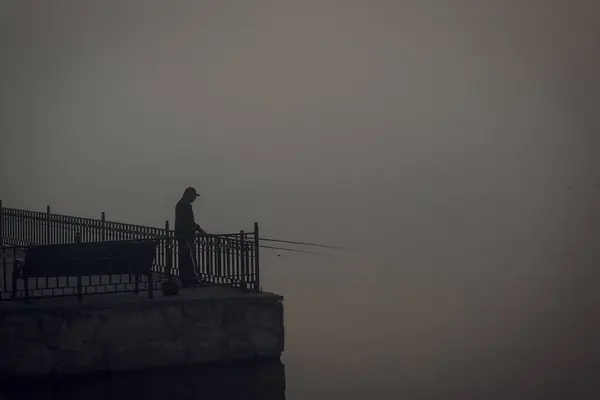 Starý muž rybaří v chladném mlhavém ránu — Stock fotografie
