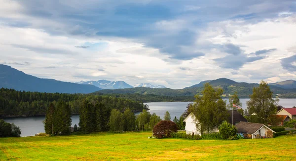 Haus am Ufer vor dem Hintergrund der schneebedeckten Berge . — Stockfoto