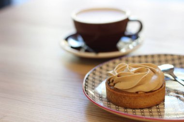 Bir fincan kahvenin yanında bir parça kek.