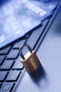 Kilitli asma kilit ve dört kredi kartı mavi bilgisayar klavyesinde. E-ticaret verileri ve ebankacılık koruması, İnternet ve finans güvenlik kavramı.