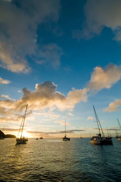 Günbatımında gemiler tropik körfezde demirliyor. Alacakaranlıkta deniz suyunda küçük yatlar ve katamaranlar. Santa Lucia 'da. Karayip yaşam tarzı temaları.