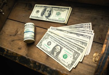 Bir tomar para ve ahşap çekmecede yuvarlanan Amerikan banknotlarının miktarı. Yüz dolarlık banknotlar, kağıt para geçmişi..