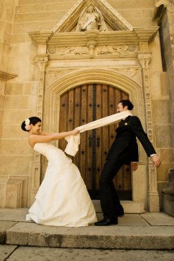 Muhteşem düğün çifti (gelin ve damat) tarihi kilise girişinin önündeki merdivenlerde duruyor ve eğleniyorlar..