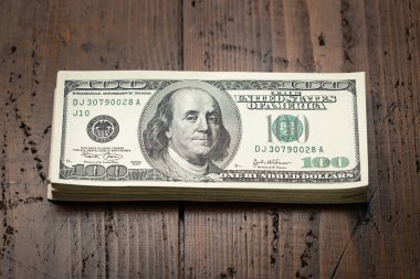 Bir para yığını, üzerinde Başkan Franklin 'in portresi olan 100 banknotu ahşap masa arkasına yığdı. Yüz dolarlık banknotlar, kağıt para birimi..