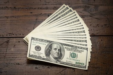 Bir para yığını, üzerinde Başkan Franklin 'in portresi bulunan 100 ABD banknotunu ahşap masa arkasına yığdı. Yüz dolarlık banknotlar, kağıt para birimi..