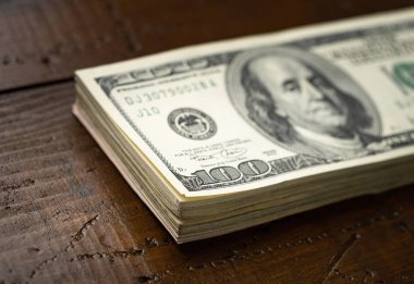 Bir para yığını, üzerinde Başkan Franklin 'in portresi olan 100 banknotu ahşap masa arkasına yığdı. Yüz dolarlık banknotlar, kağıt para birimi..