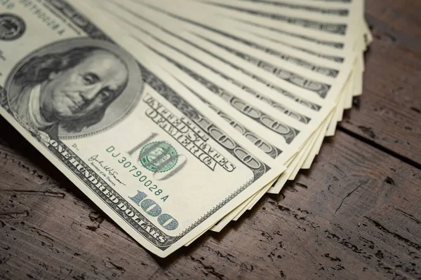 Bir para yığını, üzerinde Başkan Franklin 'in portresi bulunan 100 ABD banknotunu ahşap masa arkasına yığdı. Yüz dolarlık banknotlar, kağıt para birimi..