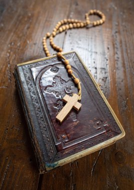 Çarmıhlı tespih kırsal ahşap masada eski bir İncil kitabının üzerinde duruyordu. Hıristiyanlık, din, dini sembol. Dua et..