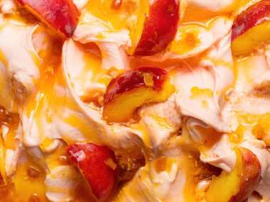 Donmuş şeftali aromalı dondurma, tam çerçeve ayrıntısı. Turuncu-kırmızı meyve parçalarıyla kaplı bej bir dondurma yüzey dokusunu kapat.