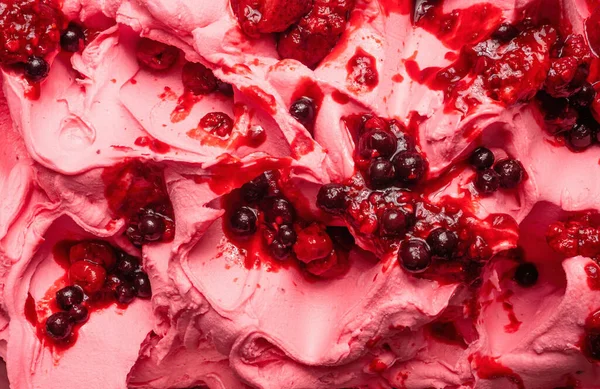 Frozen Forest Fruits flavour gelato - full frame detail. Close up of a pink surface texture of Ice cream covered with pieces of red fruit.