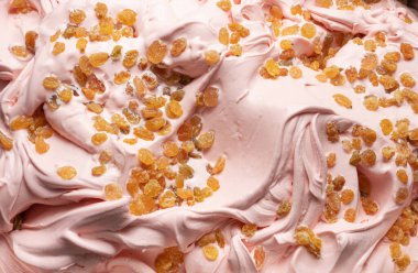 Meyve aromalı dondurma - tüm çerçeve ayrıntıları. Üzüm parçalarıyla kaplı dondurmanın pembe yüzey dokusunu kapat..