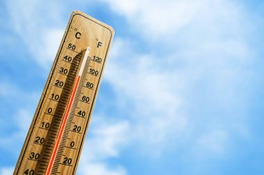 Tahta termometre ve kırmızı ölçüm sıvısı, bulutlu mavi gökyüzünün arka planında 32 derecenin üzerinde sıcaklık gösteriyor. Sıcak hava dalgası, sıcak hava, küresel ısınma, iklim değişikliği kavramı.