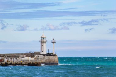 Yalta deniz fenerine karşı yuvarlanan deniz ve akşam alacakaranlığı.