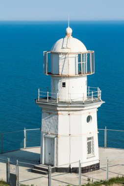Güneşli bir günde Cape Meganom 'da deniz feneri. Deniz feneri bekçisinin yıkılmış evi..