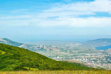 Kırım dağlarının panoramik manzarası, ilkbahar güneşli bir günde doğa. Sudak şehrinin Kırım Yarımadası üzerindeki görüntüsü.