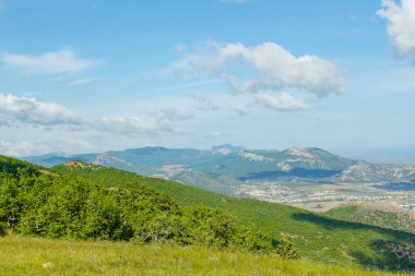 Kırım dağlarının panoramik manzarası, ilkbahar güneşli bir günde doğa. Sudak şehrinin Kırım Yarımadası üzerindeki görüntüsü.