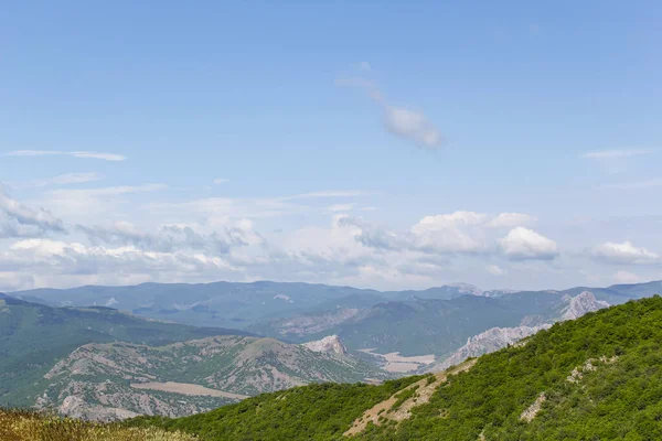 Kırım dağlarının panoramik manzarası, ilkbahar güneşli bir günde doğa. Sudak şehrinin Kırım Yarımadası üzerindeki görüntüsü.