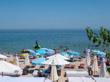 Karadeniz 'deki sahildeki insanlar. Odessa şehir plajlarında dinlenin. Kumsalın ve denizin arka planına karşı plaj kafeleri..
