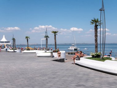 Karadeniz 'deki sahildeki insanlar. Odessa şehir plajlarında dinlenin. Kumsalın ve denizin arka planına karşı plaj kafeleri..