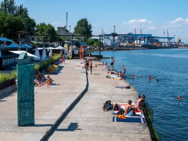 Karadeniz 'deki sahildeki insanlar. Odessa şehir plajlarında dinlenin. Kumsalın ve denizin arka planına karşı plaj kafeleri..