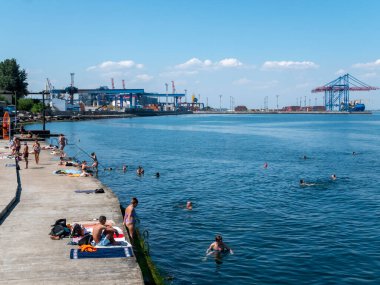 Karadeniz 'deki sahildeki insanlar. Odessa şehir plajlarında dinlenin. Kumsalın ve denizin arka planına karşı plaj kafeleri..