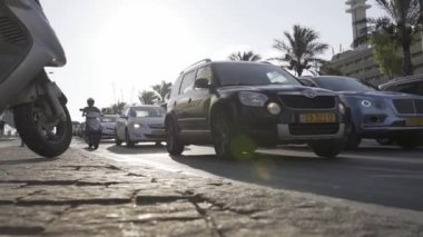 POV, kaldırımdan yol ayrımına kadar alçak açıyla çekim yapıyor. Şehir merkezi trafik taşımacılığı kavramı olarak görülüyor. Tel Aviv sokakları. İsrail.